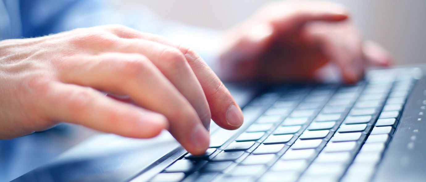 Zwei Hände schreiben auf einer Computertastatur