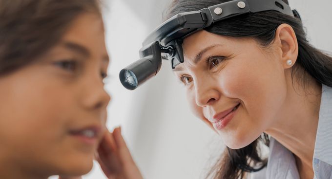 HNO-Ärztin untersucht Ohr einer jungen Patientin