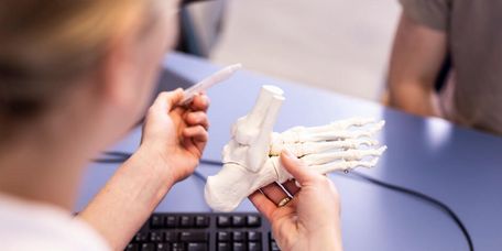 Ärztin erklärt Patienten Fußknochen am Fußmodell